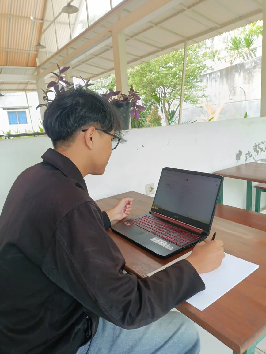 Posisi kamera yang benar: peserta, laptop, tangan, dan area kerja terlihat dari samping.